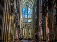 inside the dom of cologne with guests in the church pews and nice light, that comes through the colorful windows