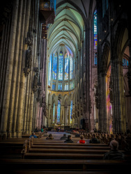 inside the dom of cologne with guests in the church pews and nice light, that comes through the colorful windows
