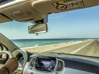 someone ist driving a fiat 500 cabrio with a view out of the car to the sea and the street near kameiros on rhodes