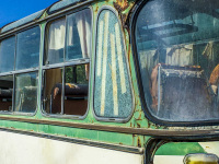 a green-white oldtimer pullman with a damaged interior is standing in a landscape of rhodes