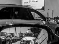at the border crossing from serbia to hungary with a view in a rear mirror, where you see traffic jam, black-and-white