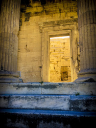 a yellow temple palast on the acropolis in athens with blue-grey steps in front of them