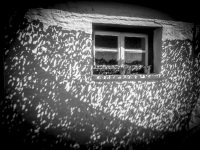 a little window at a white wall with a shadow of a camouflage net on the island of ioannina in greece, black-and-white