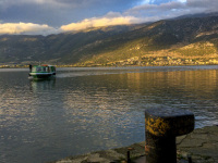 behind a rosty harbor bollard is the lake pamvotida in ioannina with a boat in a nice evening light