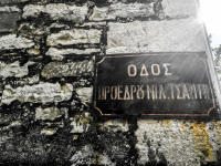 at an old house wall in doliana near ioannina hangs a sign of a streetname in greek letters