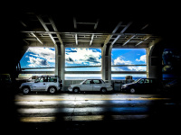 three cars are parking on the loading area on a car ferry in rio near patras, the blue sky behind it
