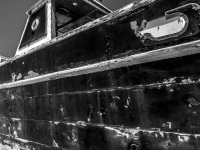the side of an old black and damaged boat at the harbor in rhodes city, black-and-white