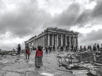 the parthenon on the acroplis in athens with a clowdy sky and a woman in a red jacket, black-and-white