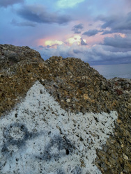 on a brown rock ist painted a big white star and in the background you see a red cloudy sky in diakopto