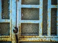 a part of a light blue rosty metal door in agios isidoros on rhodes, where a wrench ist hanging on