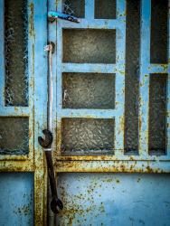 a part of a light blue rosty metal door in agios isidoros on rhodes, where a wrench ist hanging on