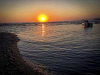 sunset at the sea of limni beach on rhodes with a boat in the sea