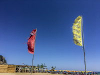 a yellow and a red beachflag in front of the blue sky at the tsambika beach on rhodes