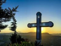 a cross on the tsambika mountain on rhodes is standing exactly in front of the sun at the sunset