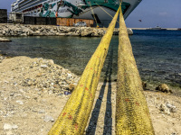 two big yellow ship ropes lead to a big cruise ship at the harbor in rhodes city