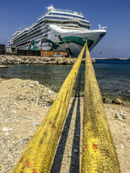 two big yellow ship ropes lead to a big cruise ship at the harbor in rhodes city