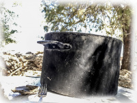 a big black metal soup pot and a fork are standing in the shadow at the beach souloudrania on rhodes