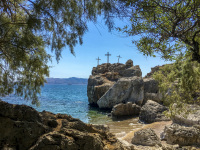 under trees sitting at the beach souloudrania with a view on thre crosses on a rock