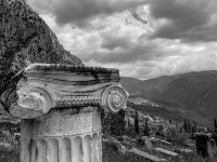 a doric column in the front and behind it you see ancient delphi and many clowds, black-and-white