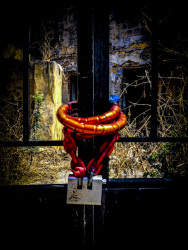 a big red lock closes a black metal door in front of an old yard in the old town of rhodes city