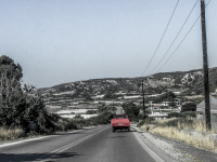 an old red pick-up is driving on the street near mandriko on rhodes