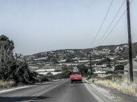 an old red pick-up is driving on the street near mandriko on rhodes