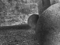 two big cannonballs are standing on a stone floor between old walls in the old town of rhodes, black-and-white