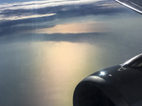 you see a part of the engine and of the wing of a plane in a evening sunny sky