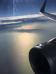 you see a part of the engine and of the wing of a plane in a evening sunny sky