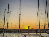 three yachts are standing in the harbor of rhodes city at sunsetligt