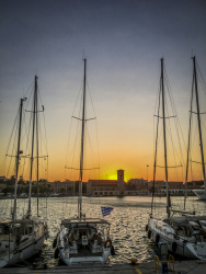 three yachts are standing in the harbor of rhodes city at sunsetligt