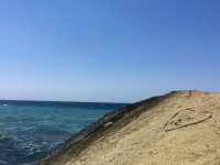 a big yellow rock in the sea at fourni beach on rhodes which is signed with a carved heart