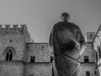a statue in front of the palace of grandmaster of the knights on rhodes, black-and-white