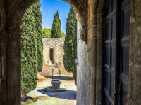 a yard with a fountain, cypresses and old walls in filerimos on rhodes