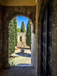 a yard with a fountain, cypresses and old walls in filerimos on rhodes