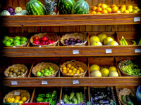 very colorful fruits and vegetables are presented in a wooden shelf for sale in lindos on rhodes