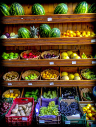 very colorful fruits and vegetables are presented in a wooden shelf for sale in lindos on rhodes