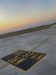 a yellow-black sign on the runway of the airport on rhodes at sunsetlight