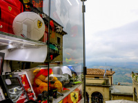 next to a store window with ferrari articles you see the landscape around san marino in italy