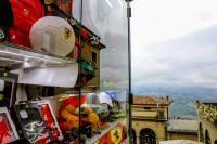 next to a store window with ferrari articles you see the landscape around san marino in italy
