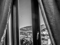 view out of a window with curtains in the landscape around bovino in puglia in italy, black-and-white