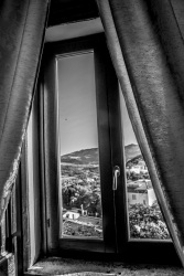 view out of a window with curtains in the landscape around bovino in puglia in italy, black-and-white