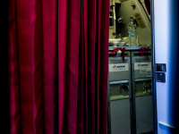 next to a red curtain you see the kitchen of the cabin crew in a plane of aegean airlines in hamburg in germany