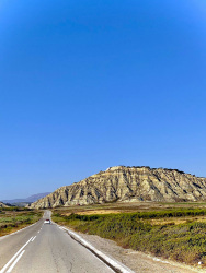 a fiat 500 drives on a lonely long street under a lovely blue sky near apolakkia on rhodes