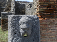 a face fountain between the walls in the archaeological site pompeii near naples in italy