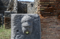 a face fountain between the walls in the archaeological site pompeii near naples in italy