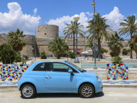 a light blue fiat 500 in front of the castle of manfredonia in italy