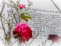 roses are in the front of a memorial stone which is signed with the names of the victims of the massacre in kalavrita in WW2