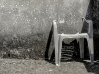 a damaged chair ist leaning at a wall and shadows it in geroplatanos in epirus, black-and-white