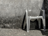 a damaged chair ist leaning at a wall and shadows it in geroplatanos in epirus, black-and-white
